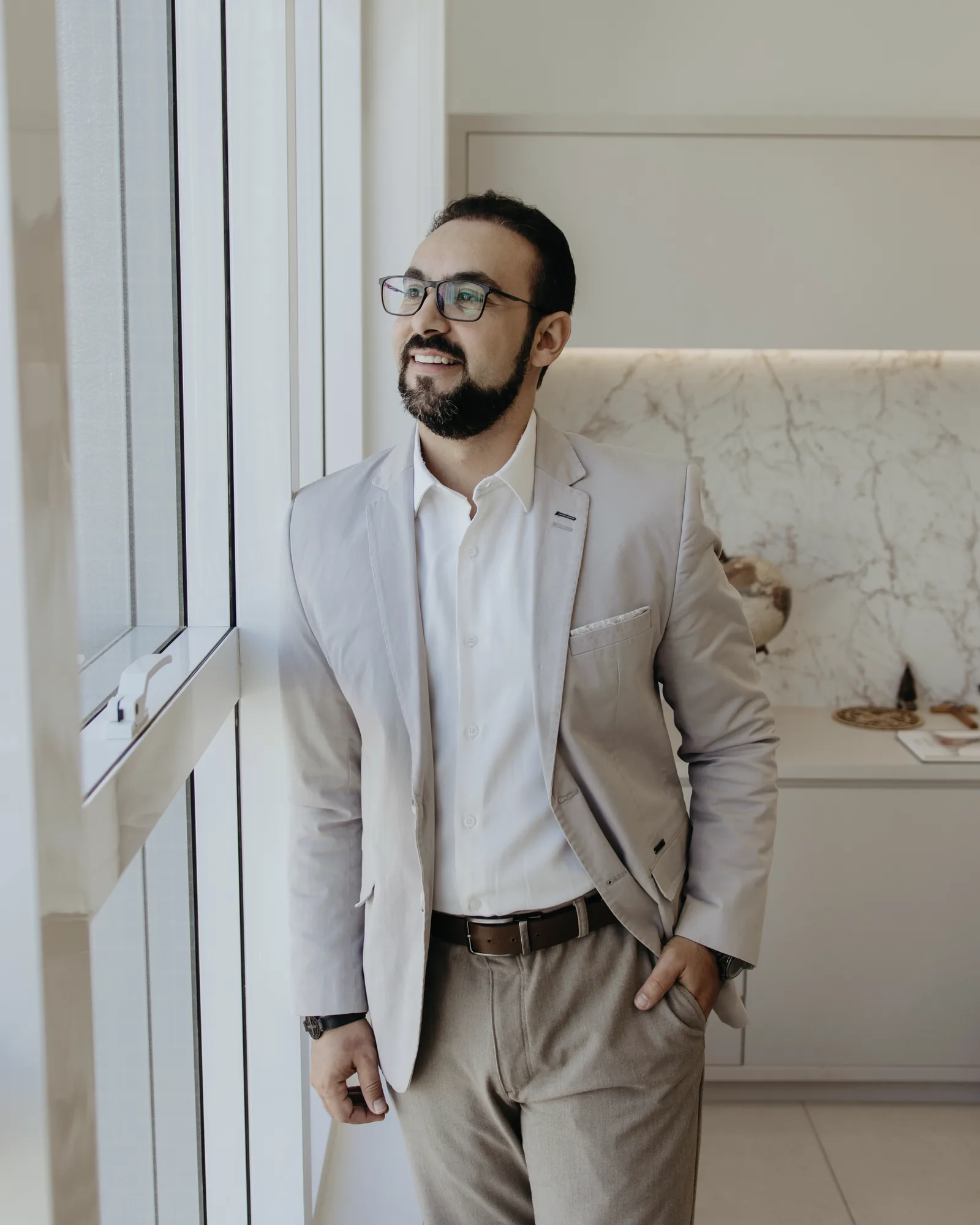 Dr. Guilherme Antonangelo sorrindo junto à janela do consultório